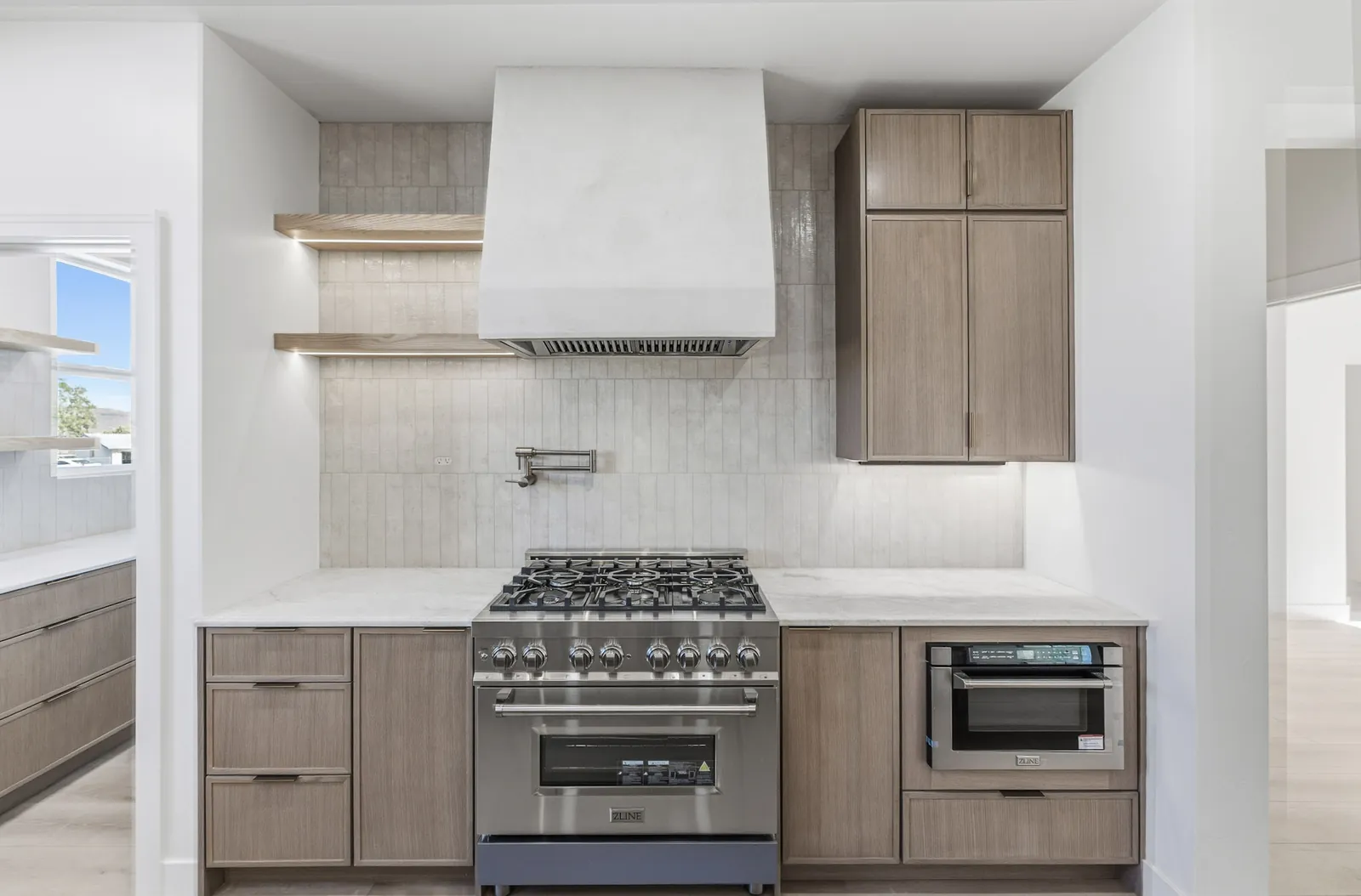 Finished kitchen with a lime plaster range hood, white oak cabinets and open shelving