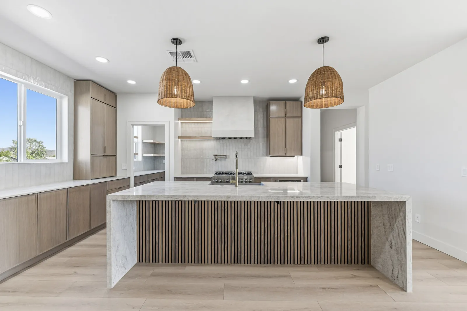 Kitchen with a marble waterfall island and full height white oak cabinetry