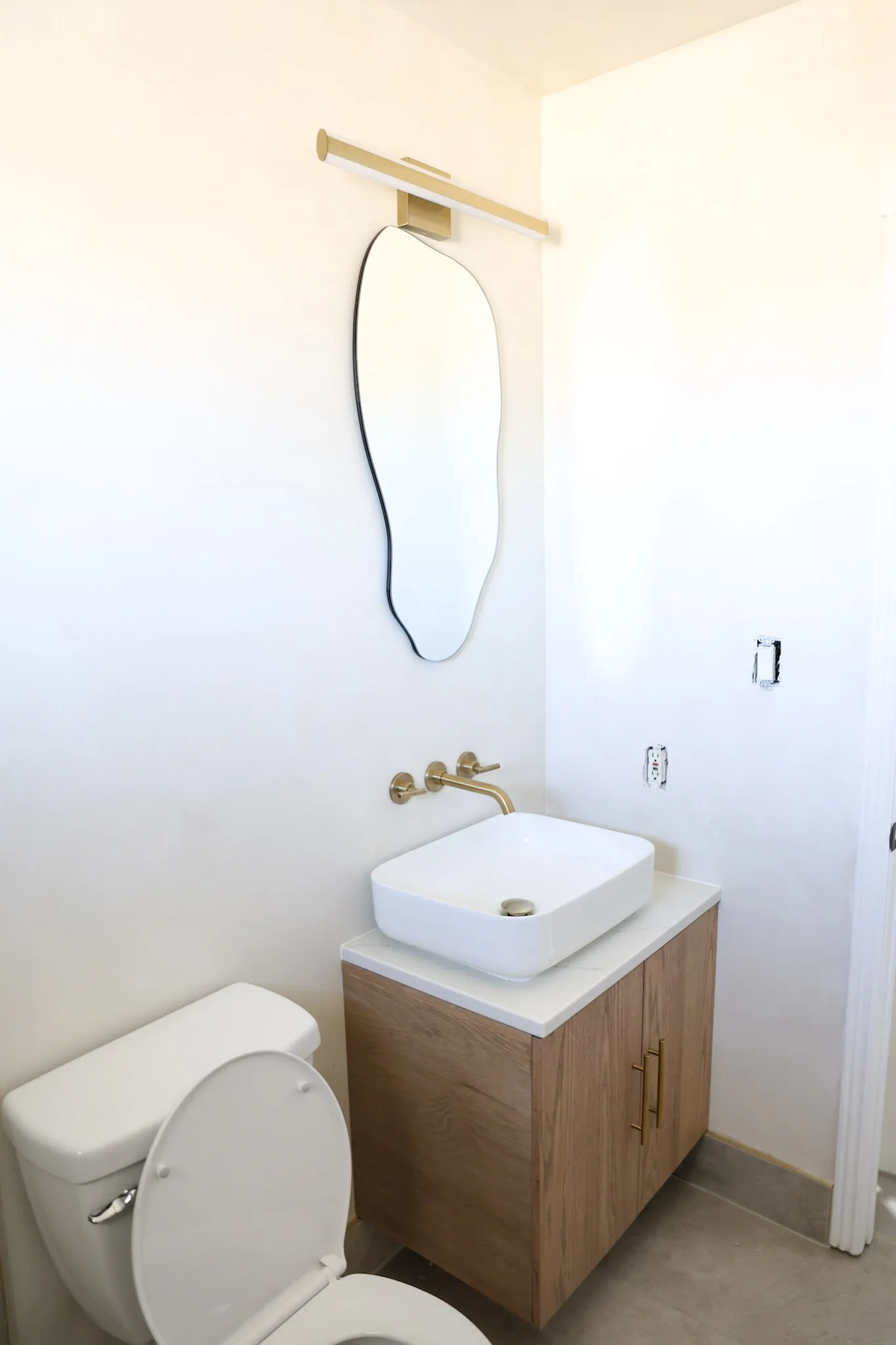 Powder room with an oak vanity, stone vessel sink and a slim brass tap